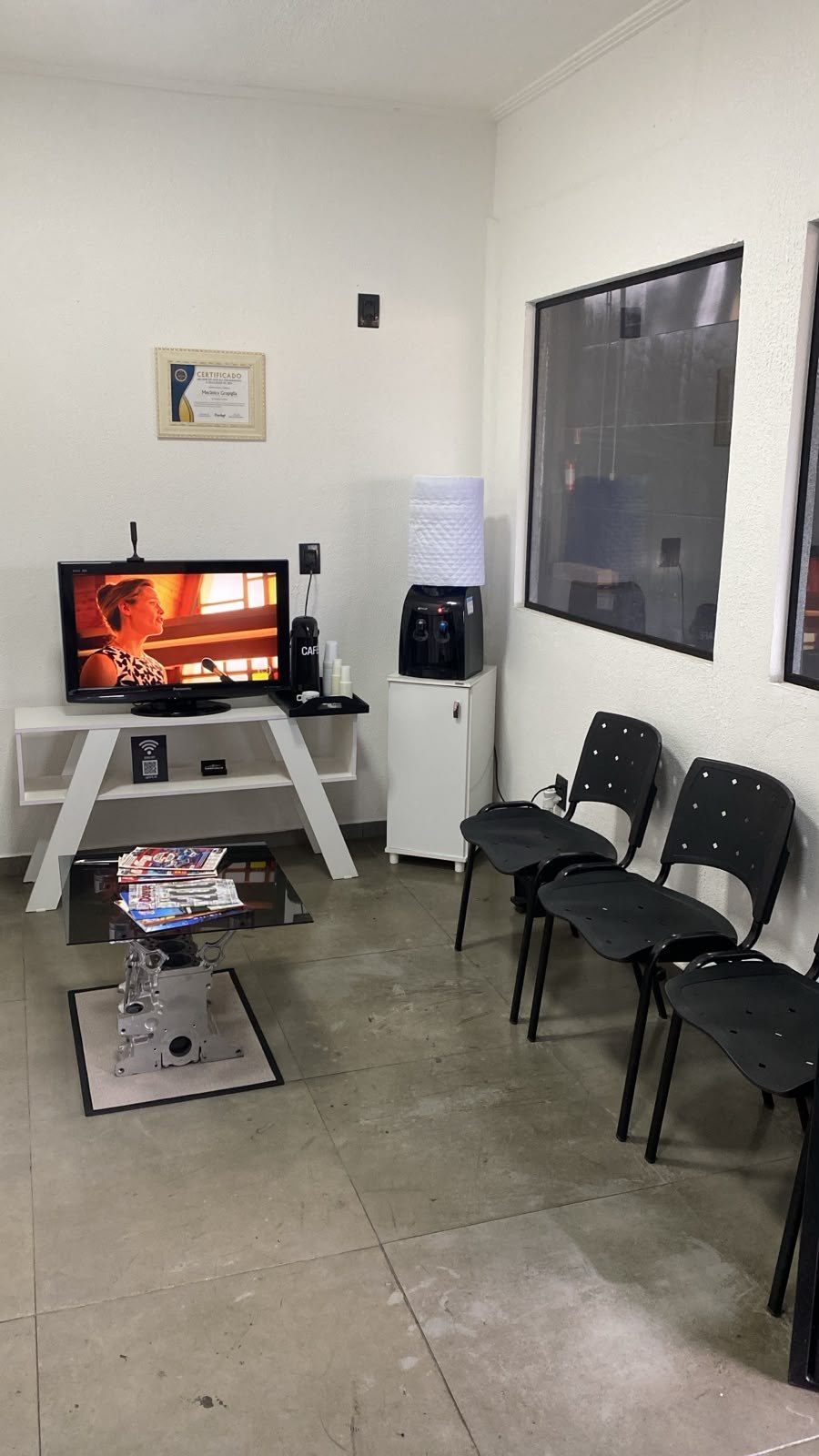 Sala de espera da Grapiglia com cadeiras, televisão, café e água